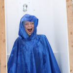 Child in a rain poncho having water poured on them at the Childrens' Water Festival
