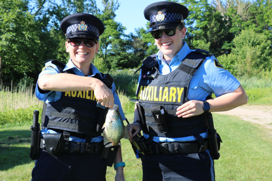 OPP Auxiliary Volunteers holding a fish at the Lake Whittaker fishing derby