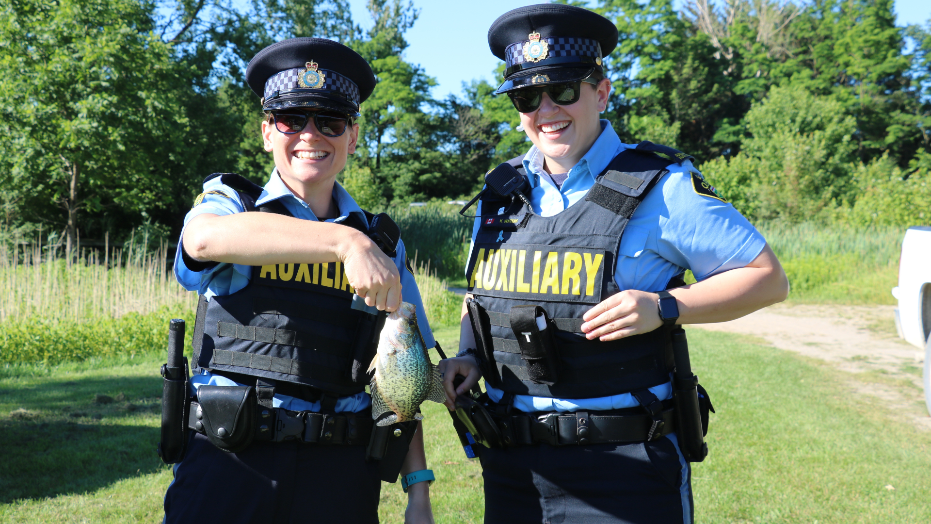 OPP Auxiliary Volunteers holding a fish at the Lake Whittaker fishing derby